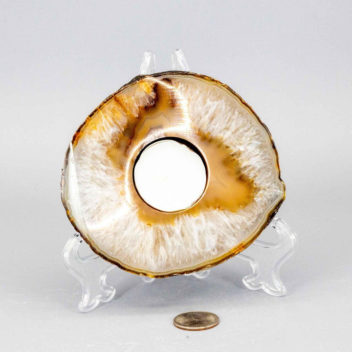 Thick, polished Agate slice tea light candle holder with natural amber and white banding, displayed on a stand.