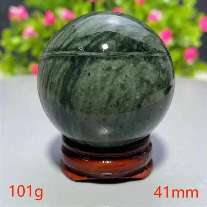 Polished dark green Tibetan Jade Crystal Sphere from Crystal Destiny, weighing 101g and measuring 41mm, on a wooden stand.