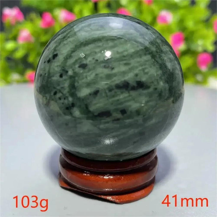 Smooth, polished dark green Tibetan Jade Crystal Sphere on a wooden stand from Crystal Destiny.