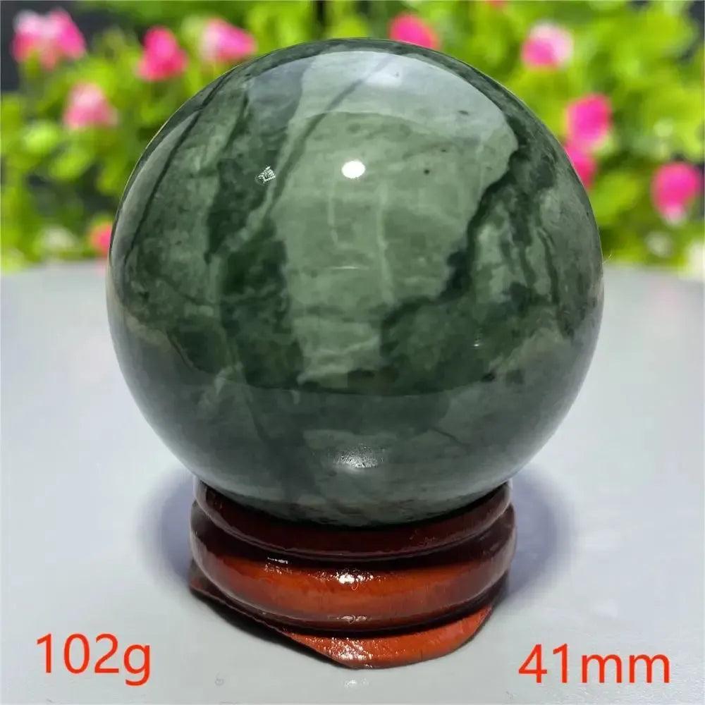 Smooth, polished dark green Tibetan Jade Crystal Sphere (102g, 41mm) on a wooden stand from Crystal Destiny.