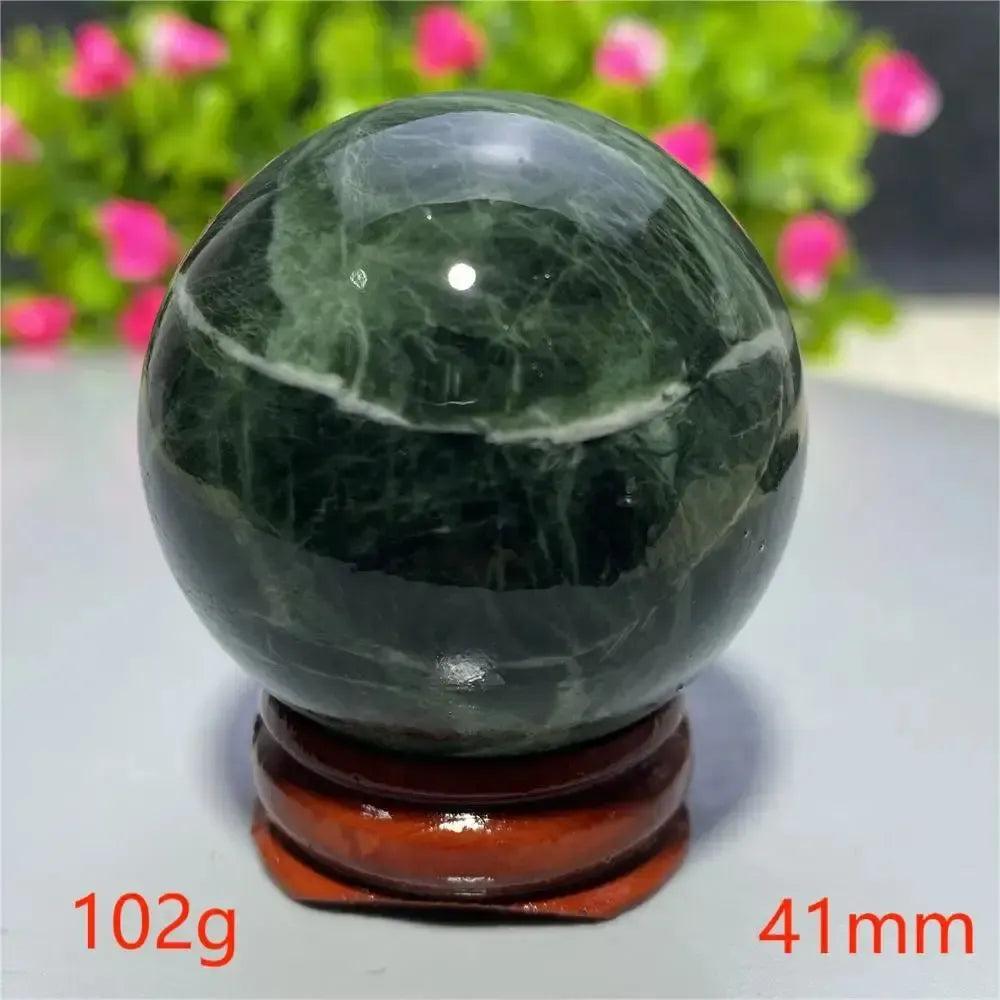 Smooth, polished dark green Tibetan Jade Crystal Sphere (41mm, 102g) on a wooden stand, from Crystal Destiny.
