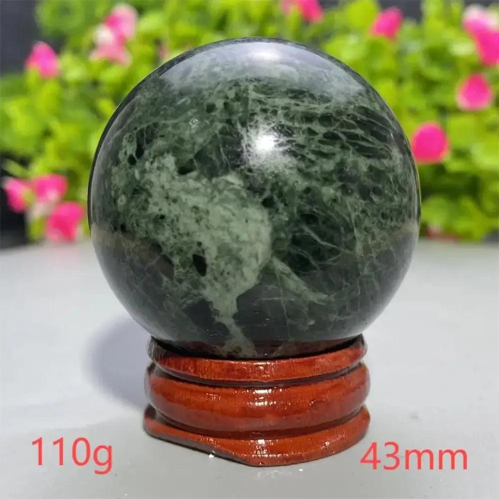Polished dark green Tibetan Jade Crystal Sphere with natural patterns on a wooden stand from Crystal Destiny.