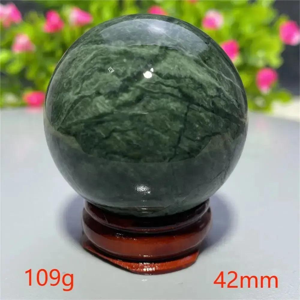 Smooth, polished dark green Tibetan Jade Crystal Sphere (42mm, 109g) on a wooden stand from Crystal Destiny.