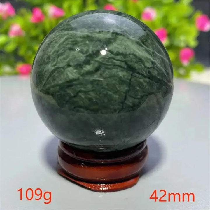 Smooth, polished dark green Tibetan Jade Crystal Sphere (42mm, 109g) on a wooden stand from Crystal Destiny.