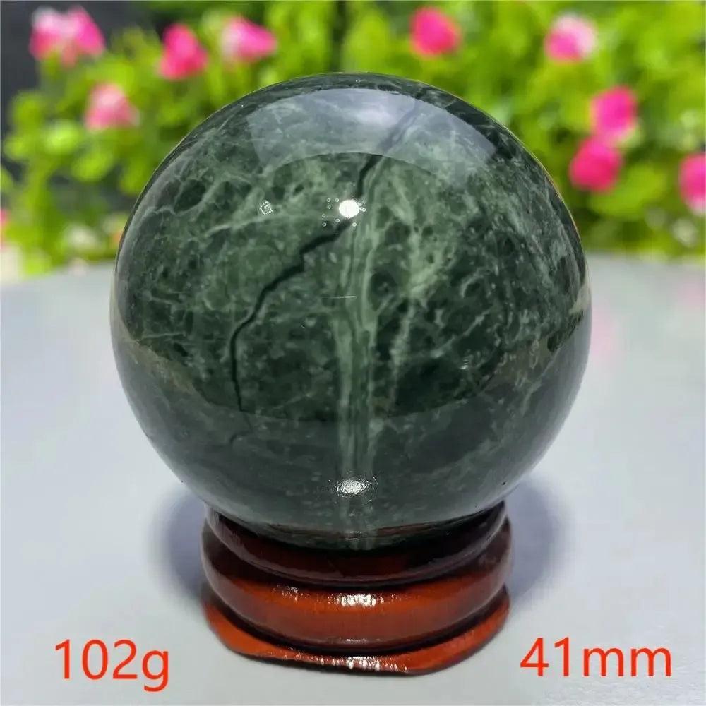 Polished dark green Tibetan Jade crystal sphere on a wooden stand from Crystal Destiny, promoting peace and vitality.