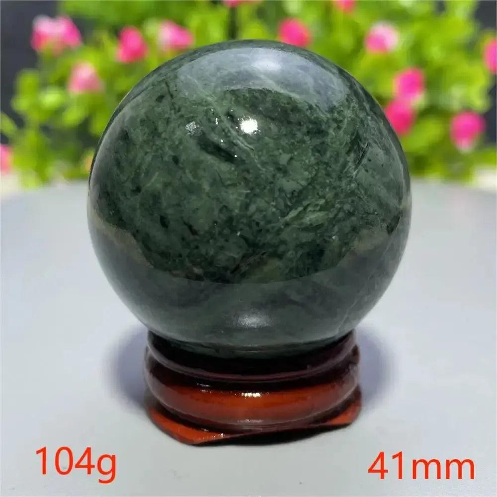 Smooth, polished dark green Tibetan Jade crystal sphere on a wooden stand from Crystal Destiny.
