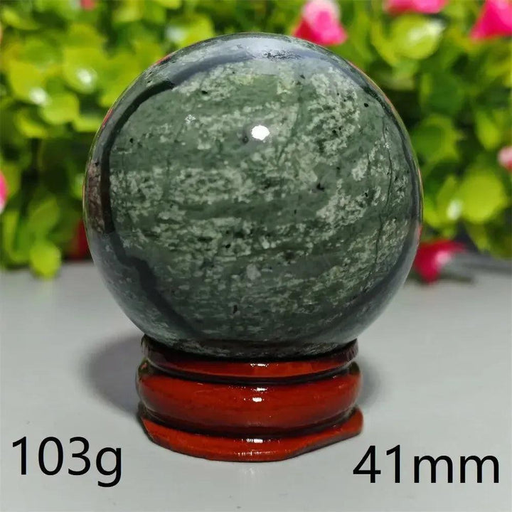 Polished Tibetan Jade Crystal Sphere (103g, 41mm) on a red stand, showcasing earthy green tones. Crystal Destiny.