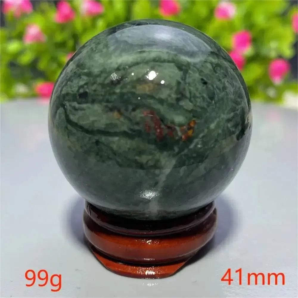 Polished dark green Tibetan Jade Crystal Sphere with natural patterns on a wooden stand from Crystal Destiny.