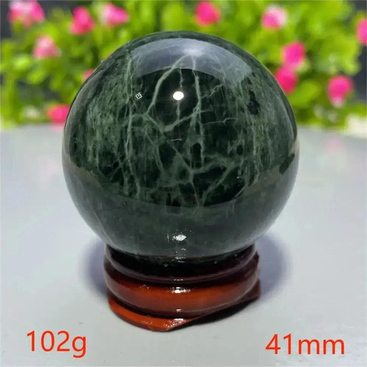 Polished dark green Tibetan Jade Crystal Sphere with white veins on a wooden stand from Crystal Destiny.