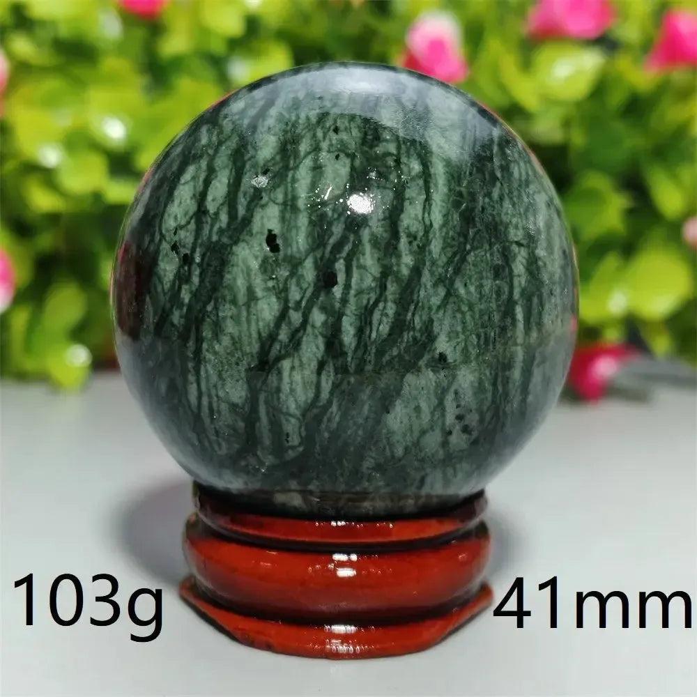 Polished dark green Tibetan Jade Crystal Sphere (103g, 41mm) on a red wooden stand, promoting calm and healing.