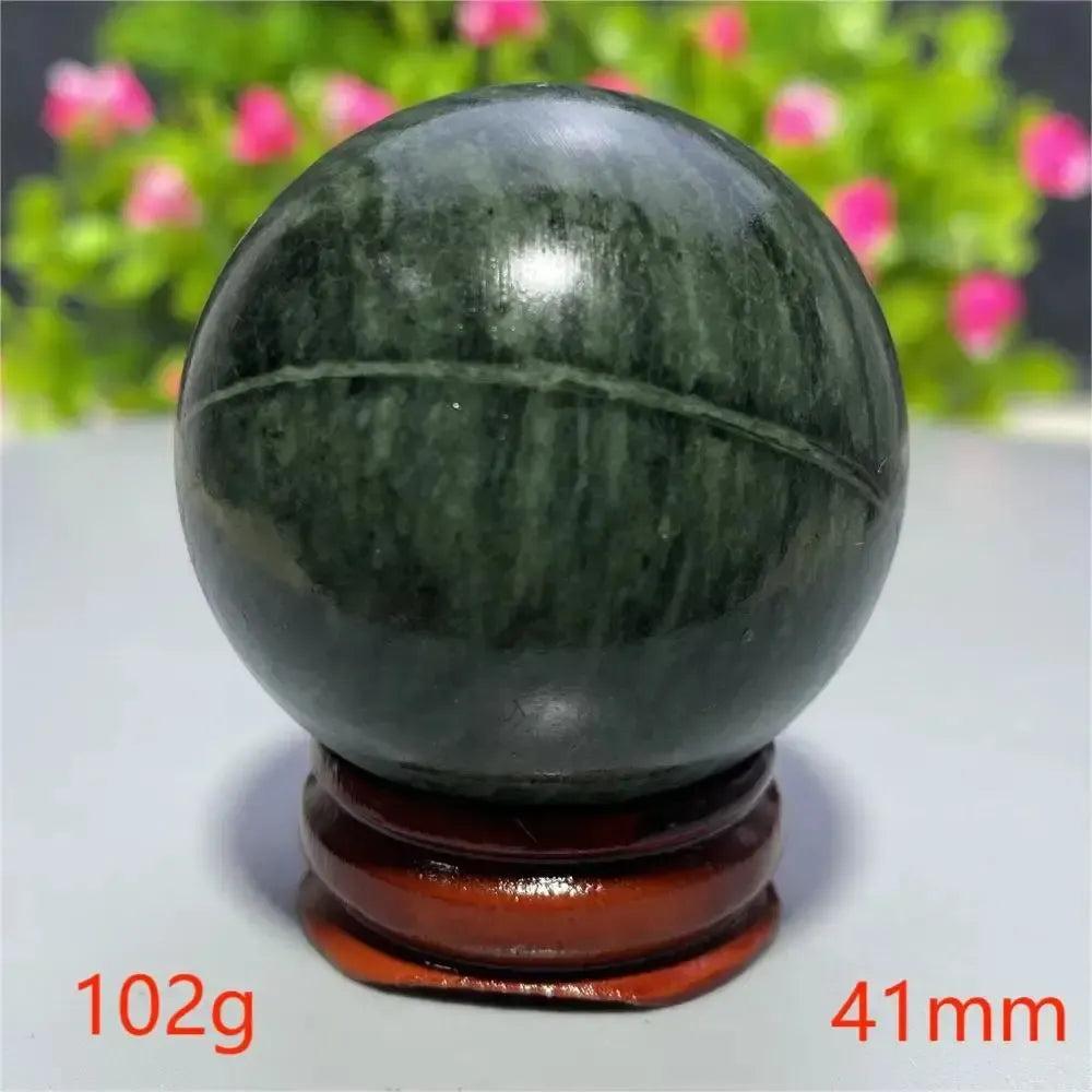 Polished dark green Tibetan Jade Crystal Sphere (41mm, 102g) on a wooden stand, promoting peace and vitality from Crystal Destiny.