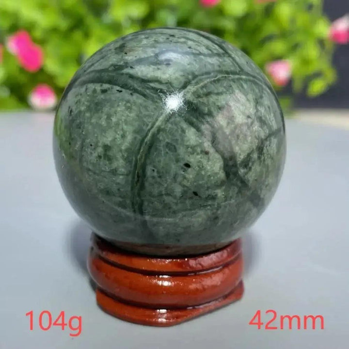 Polished 42mm dark green Tibetan Jade crystal sphere with natural patterns on a wooden stand from Crystal Destiny.