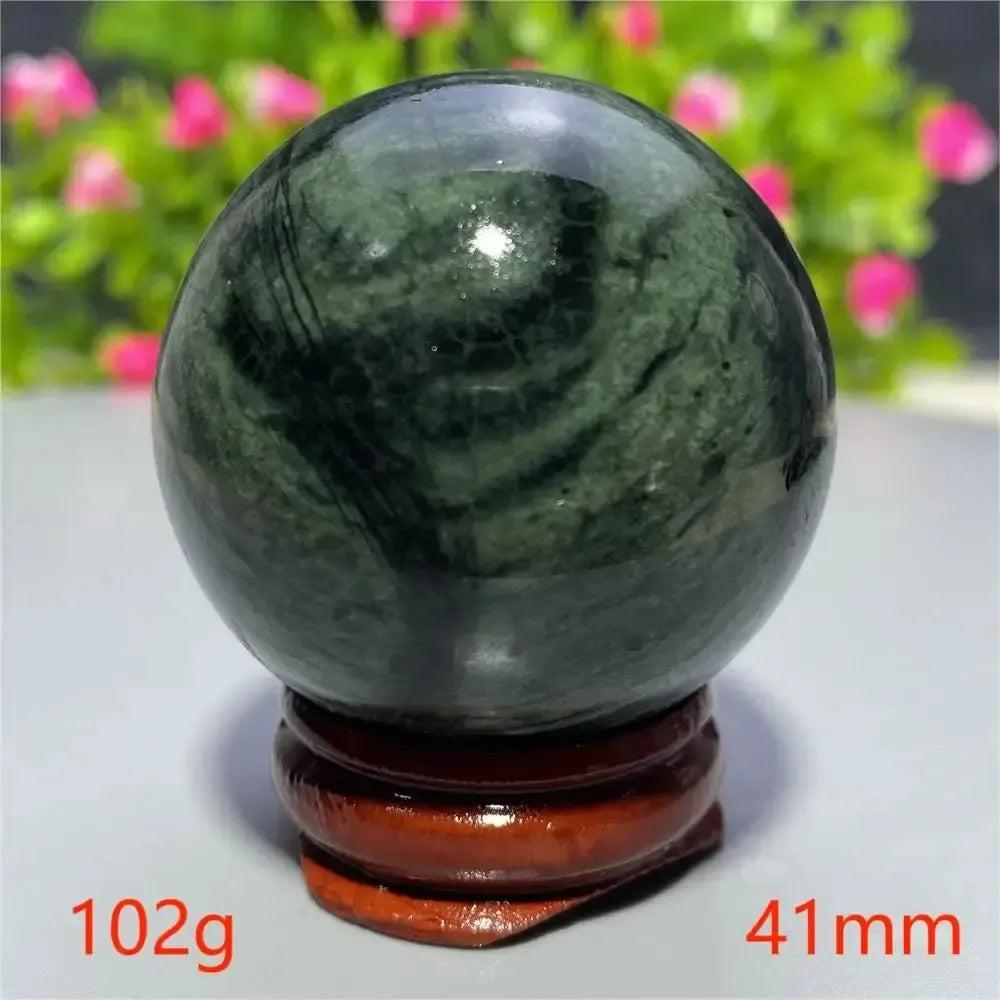 Smooth, polished dark green Tibetan Jade Crystal Sphere (41mm, 102g) on a wooden stand from Crystal Destiny.