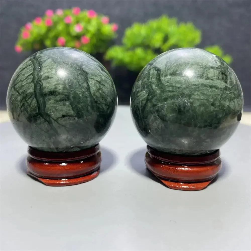 Two polished dark green Tibetan Jade crystal spheres on red wooden stands from Crystal Destiny.