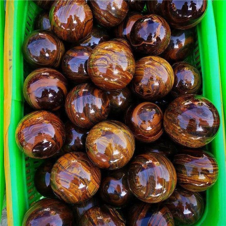 Polished Tiger Iron crystal spheres with golden shimmer, deep red, and metallic silver bands, promoting grounding.