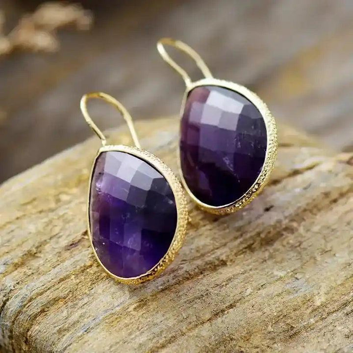 Sparkling natural amethyst teardrop dangle earrings with gold-toned settings, offering timeless sophistication and versatile style.