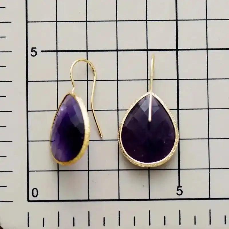 Sparkling purple amethyst teardrop dangle earrings with gold-toned settings, offering timeless sophistication and versatile style.