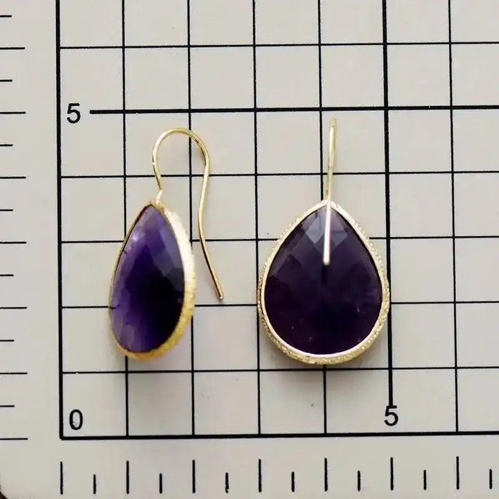 Sparkling purple amethyst teardrop dangle earrings with gold-toned settings, offering timeless sophistication and versatile style.