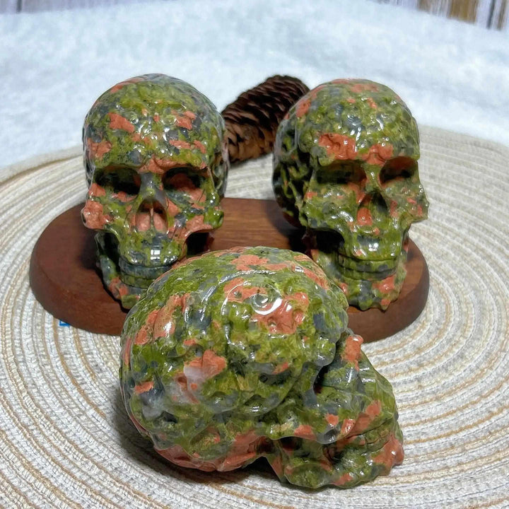 Three polished Unakite crystal skulls with green and pink patterns, perfect for Reiki healing and unique home decor.