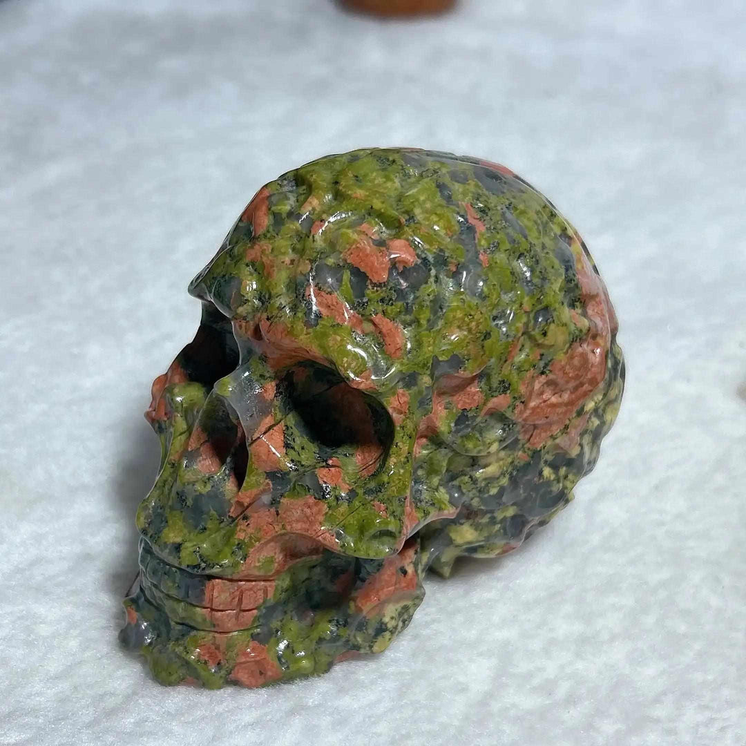 Hand-carved Unakite crystal skull with vibrant green and pink patterns, perfect for Reiki healing and unique home decor.