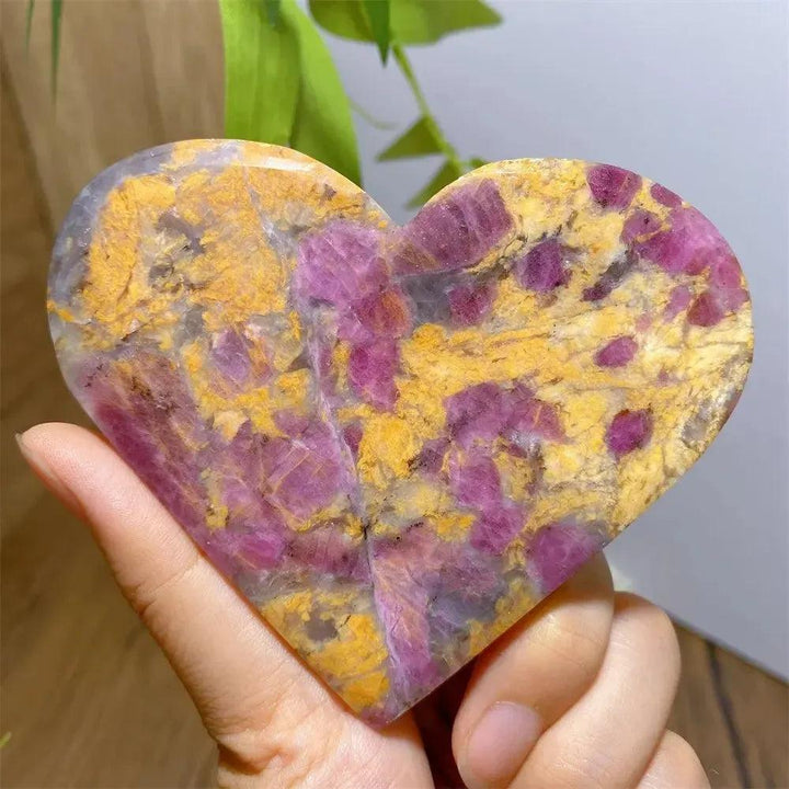 Hand-carved Unicorn Stone heart with swirling pink, purple, and yellow hues, showcasing its unique patterns.