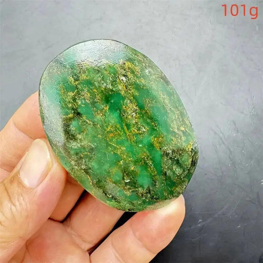 Polished Verdite crystal palm stone, deep mottled green with gold and rust flashes, held in hand.