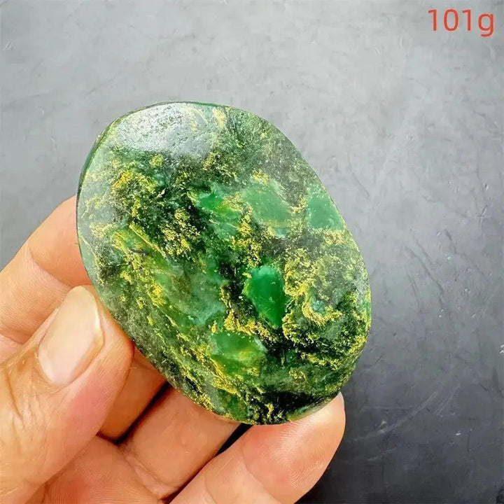 Polished Verdite crystal palm stone, deep mottled green with gold and rust flashes, held in a hand.