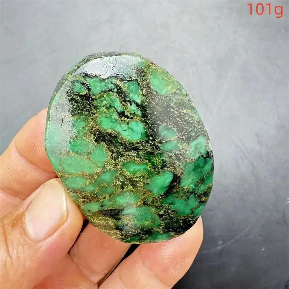 Polished Verdite crystal palm stone, deep mottled green with gold and black veins, held in hand, 101g.
