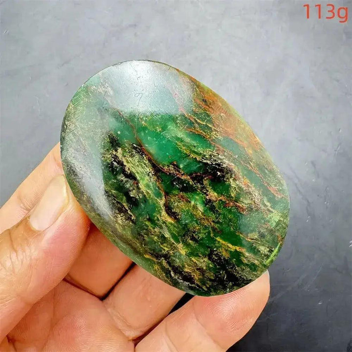 Polished Verdite palm stone, deep mottled green with flashes of gold and rust, held in a hand.