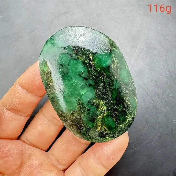 Polished Verdite crystal palm stone, deep mottled green with gold and rust flashes, held in a hand.