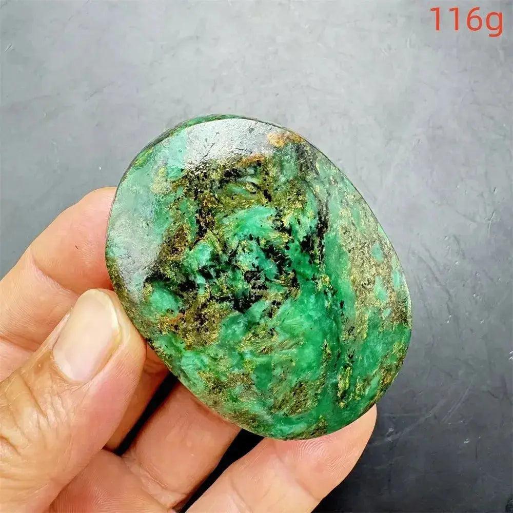 Polished Verdite palm stone, deep mottled green with gold and black flecks, held in a hand.