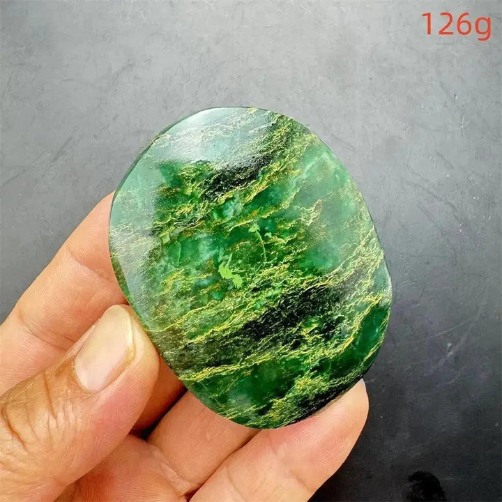 Polished Verdite palm stone, deep mottled green with gold and rust flashes, held in hand.