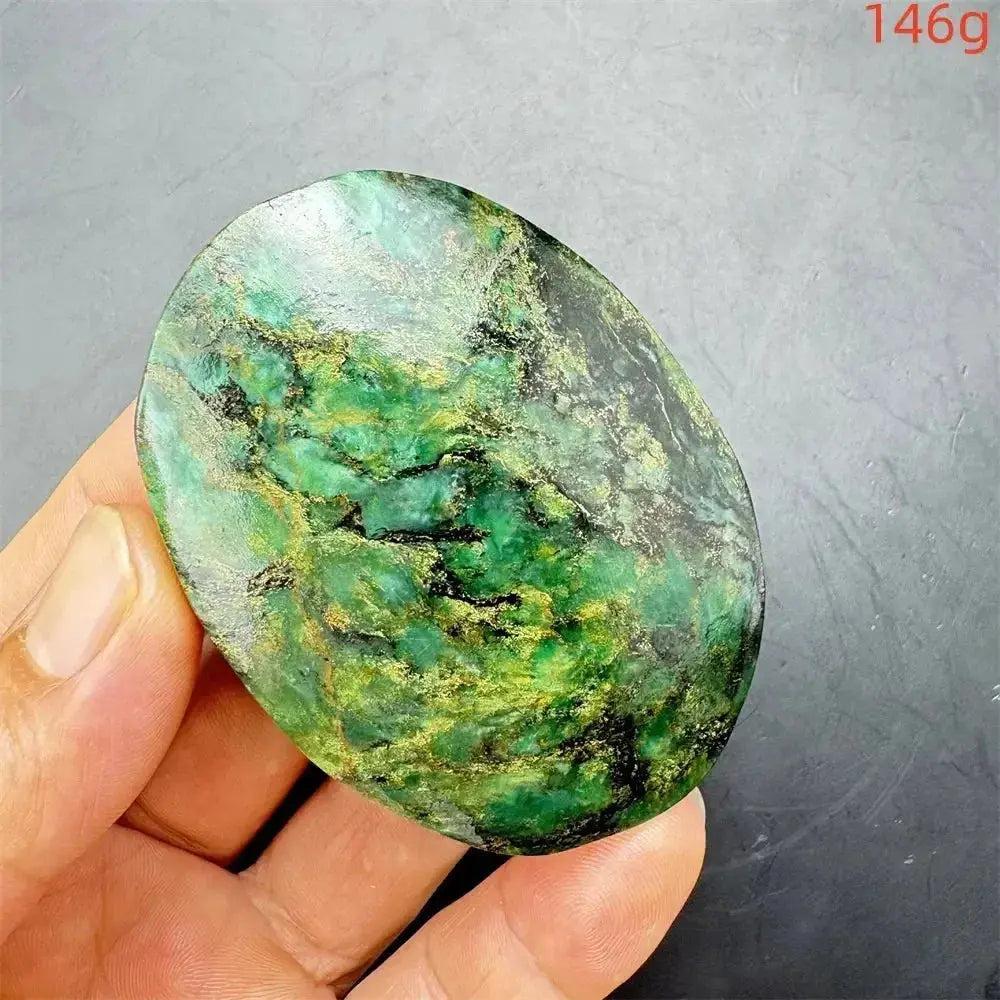 Polished Verdite palm stone, deep mottled green with gold and black veins, held in a hand.