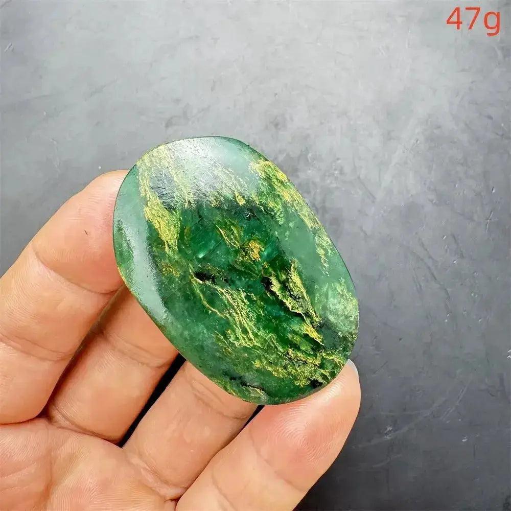 Polished Verdite crystal palm stone, deep mottled green with golden fuchsite flashes, held in a hand.