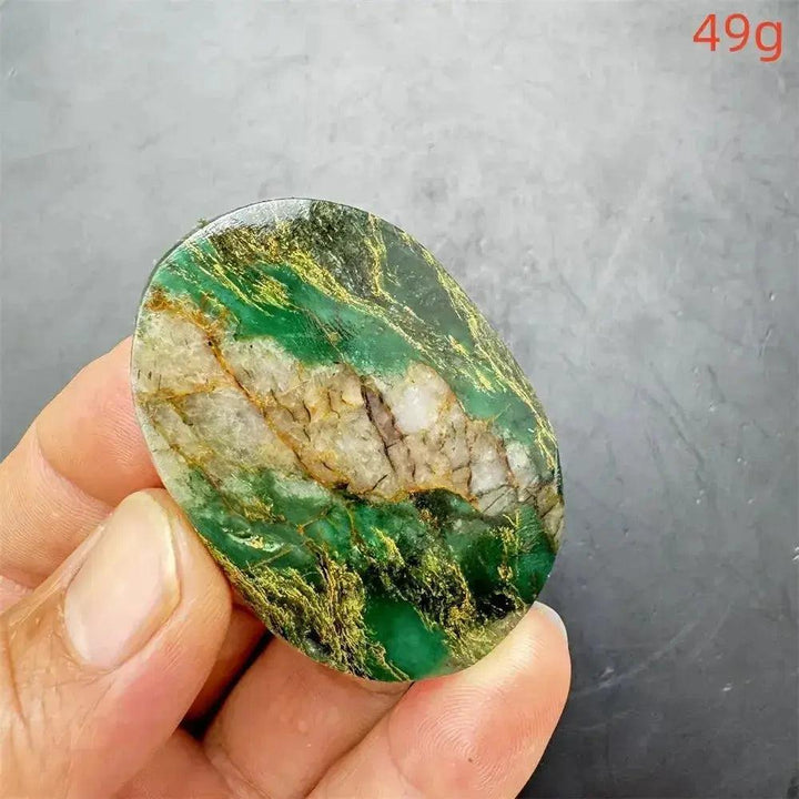 Polished Verdite palm stone with deep green, gold, and rust veins, held in a hand. Grounding and heart connection.