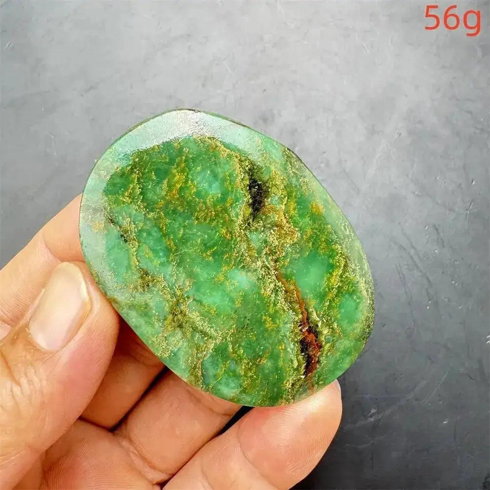 Polished Verdite crystal palm stone, deep mottled green with gold and rust flashes, held in a hand.