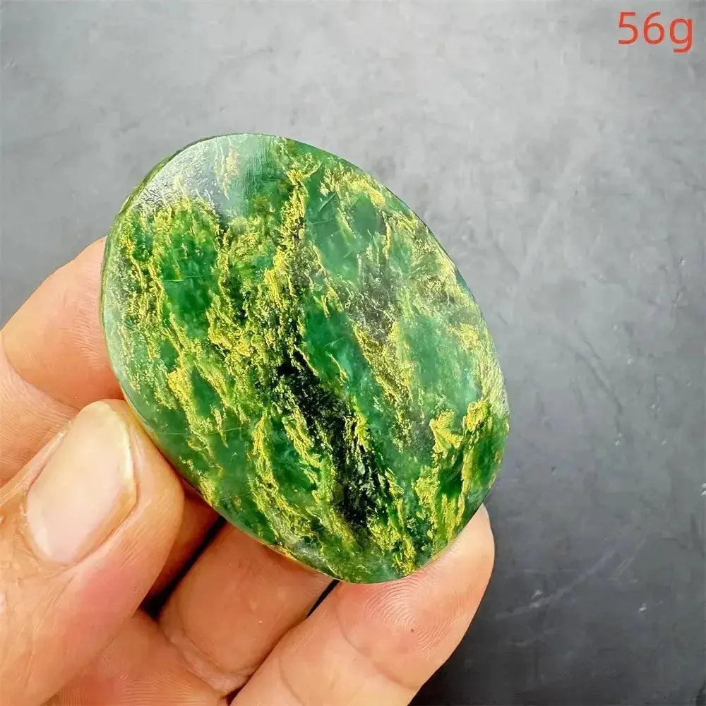 Polished Verdite crystal palm stone, deep mottled green with vibrant golden-yellow veins, held in a hand.