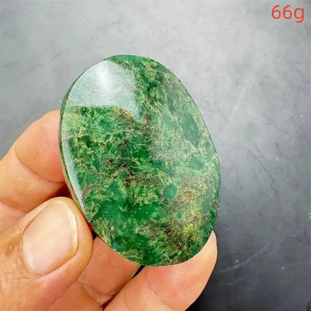 Polished Verdite crystal palm stone, deep mottled green with gold and rust flashes, held in hand.