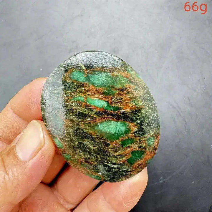 Polished Verdite crystal palm stone, deep mottled green with brown and gold streaks, held in a hand.