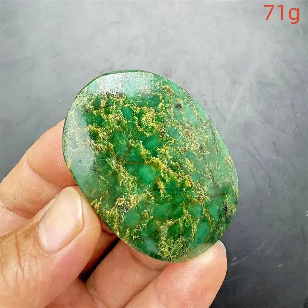 Polished Verdite crystal palm stone, deep mottled green with gold and rust flashes, held in hand.