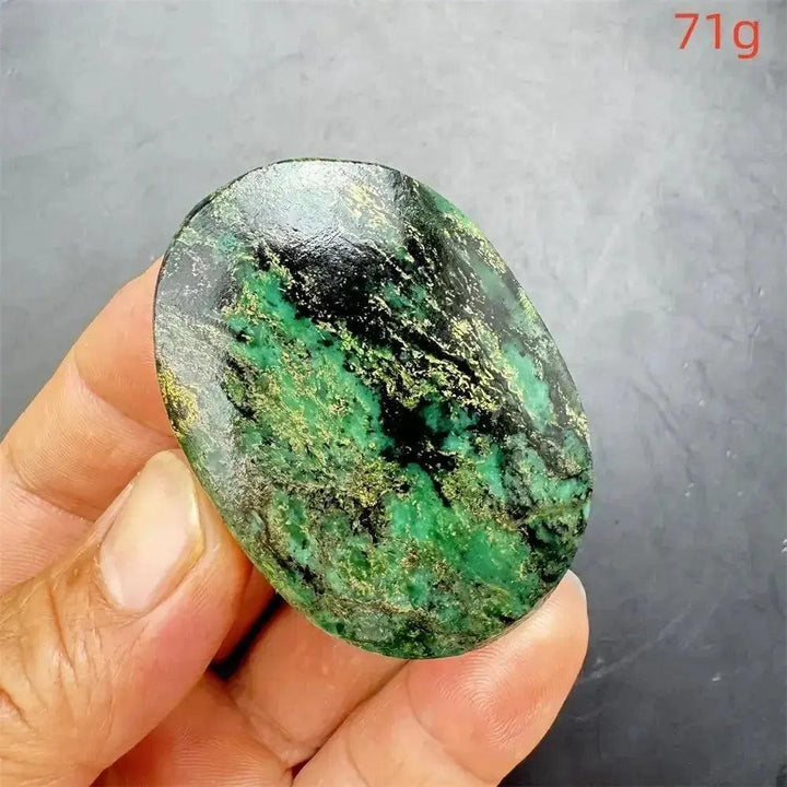 Polished Verdite crystal palm stone with deep mottled green, black, and gold flashes, held in a hand.