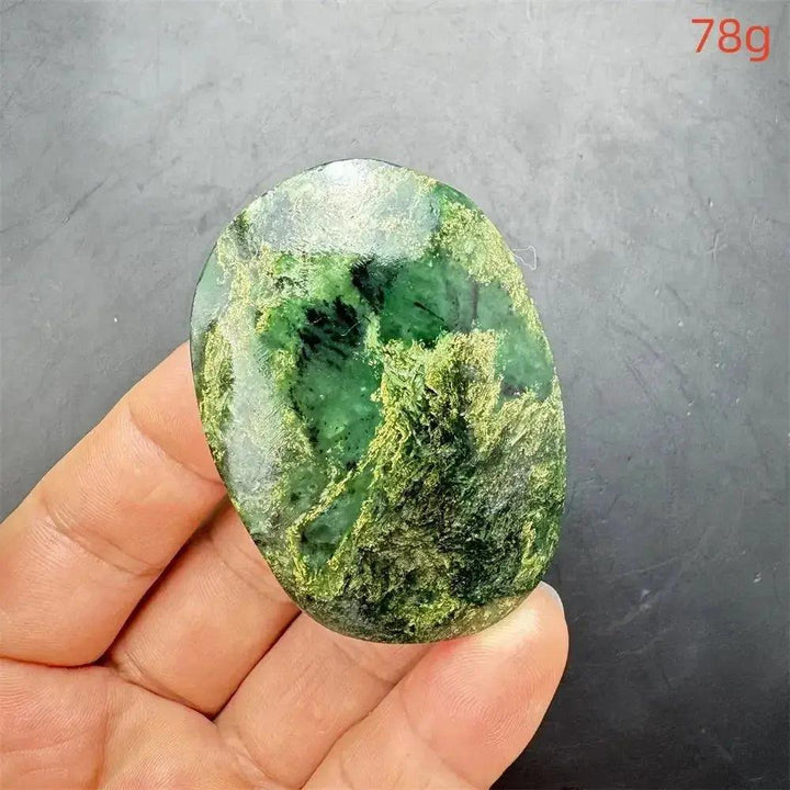 Polished Verdite crystal palm stone, deep mottled green with gold and rust flashes, held in a hand.