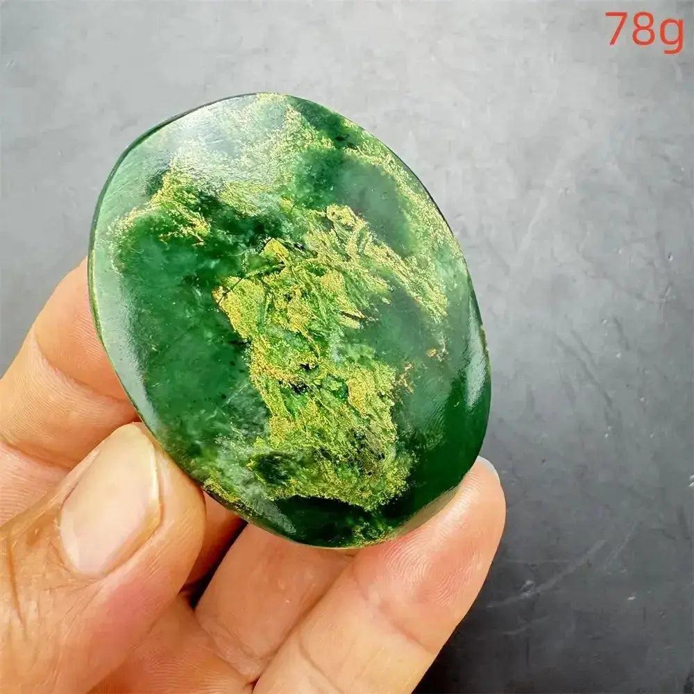 Polished Verdite crystal palm stone, deep mottled green with gold and rust flashes, held in hand.