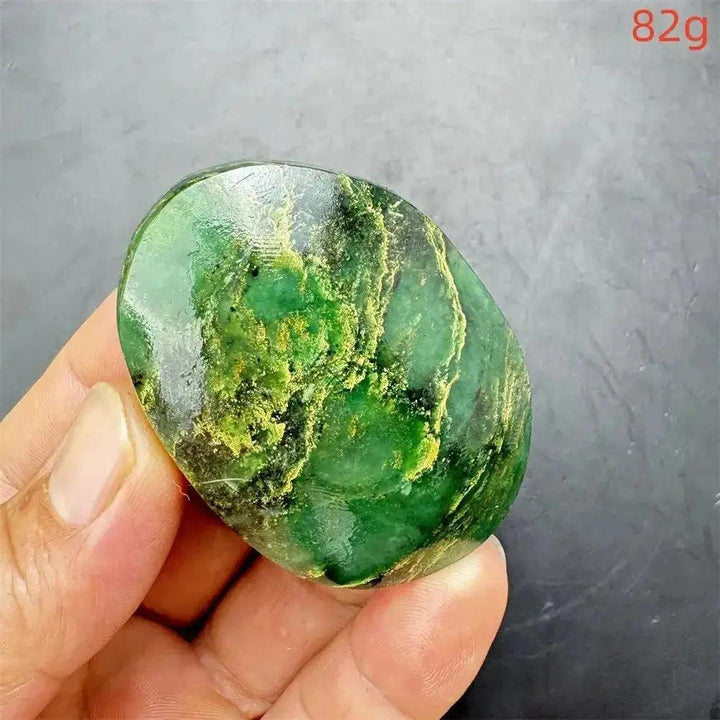Polished Verdite crystal palm stone, deep mottled green with gold and rust flashes, held in hand.