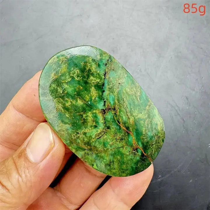 Polished Verdite crystal palm stone, deep mottled green with gold and rust flashes, held in a hand.