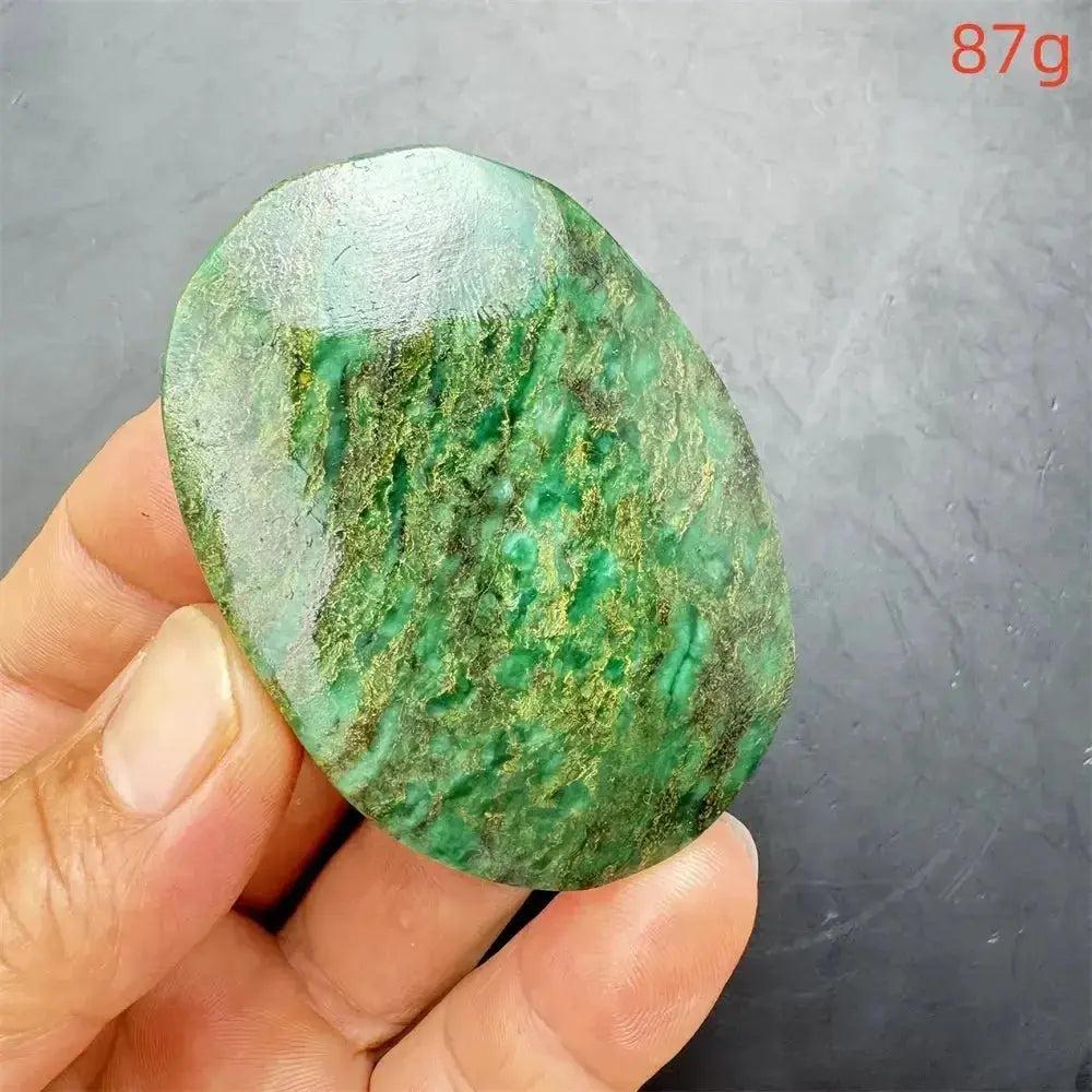 Polished Verdite palm stone, deep mottled green with gold and rust flashes, held in hand. 87g.