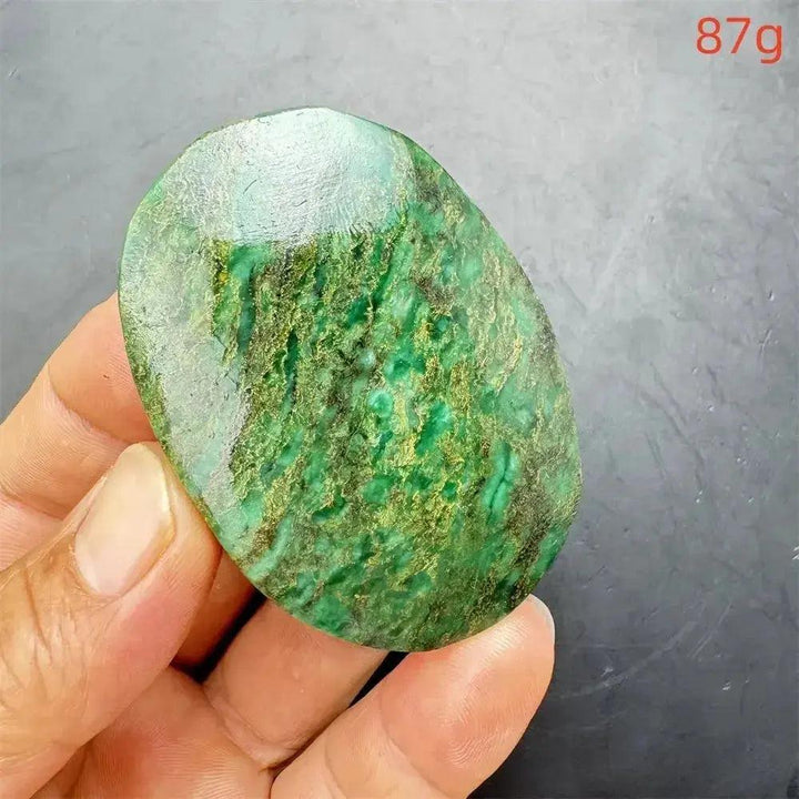 Polished Verdite palm stone, deep mottled green with gold and rust flashes, held in hand. 87g.
