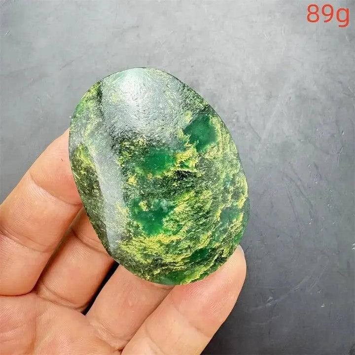 Polished Verdite crystal palm stone, deep mottled green with yellow-gold flashes, held in a hand.