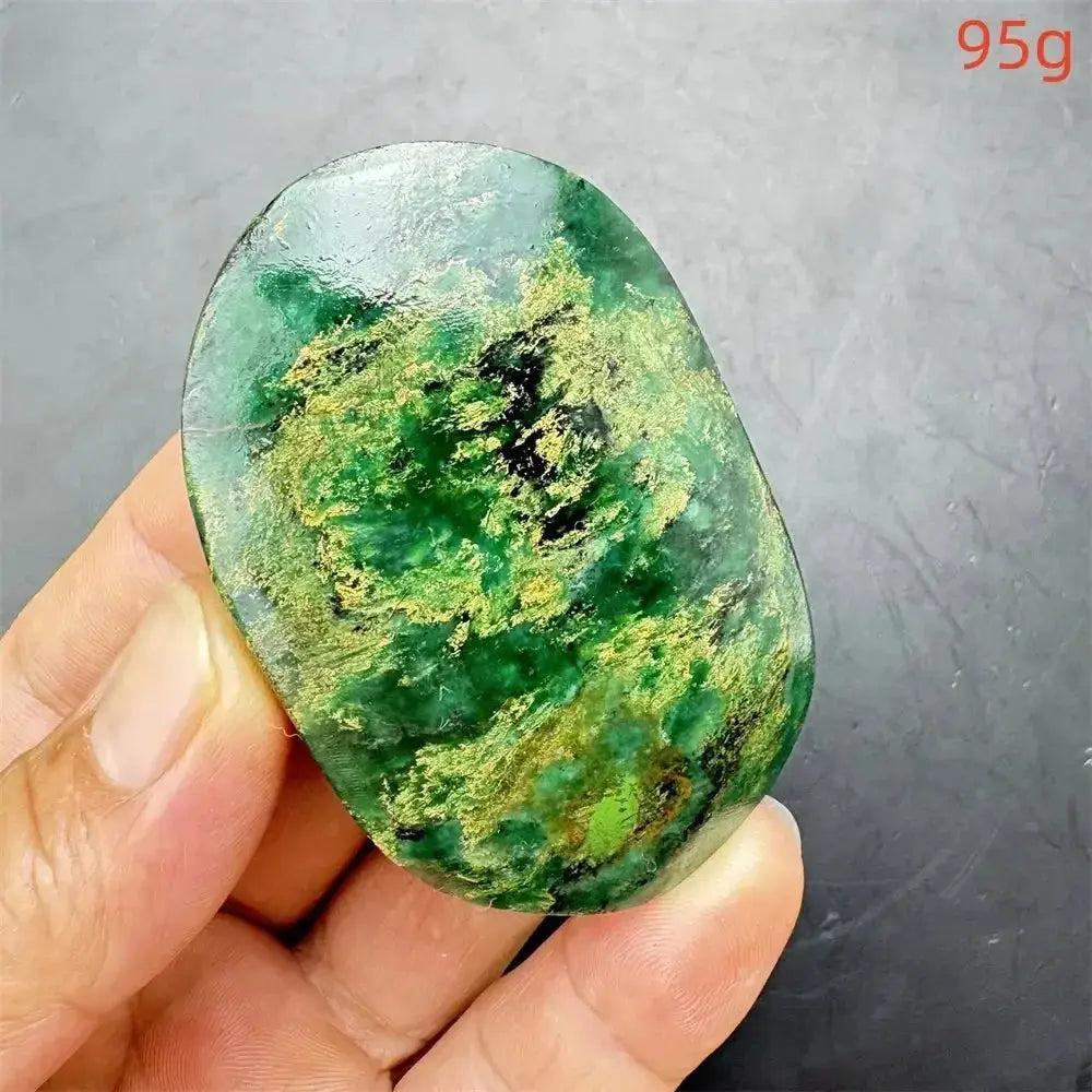 Polished Verdite palm stone, deep mottled green with gold and black flecks, held in hand, 95g.