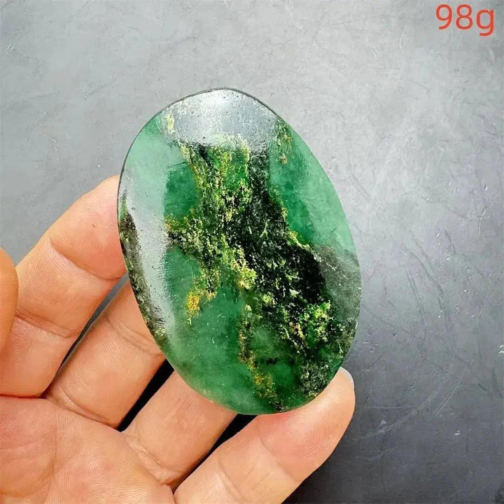 Polished Verdite crystal palm stone, deep mottled green with gold and black veins, held in a hand.